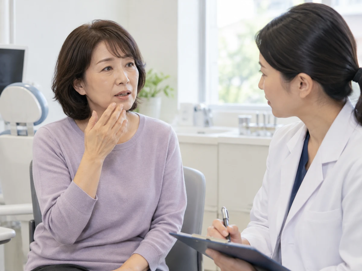 口の変化について診察室で相談する女性のイメージ写真