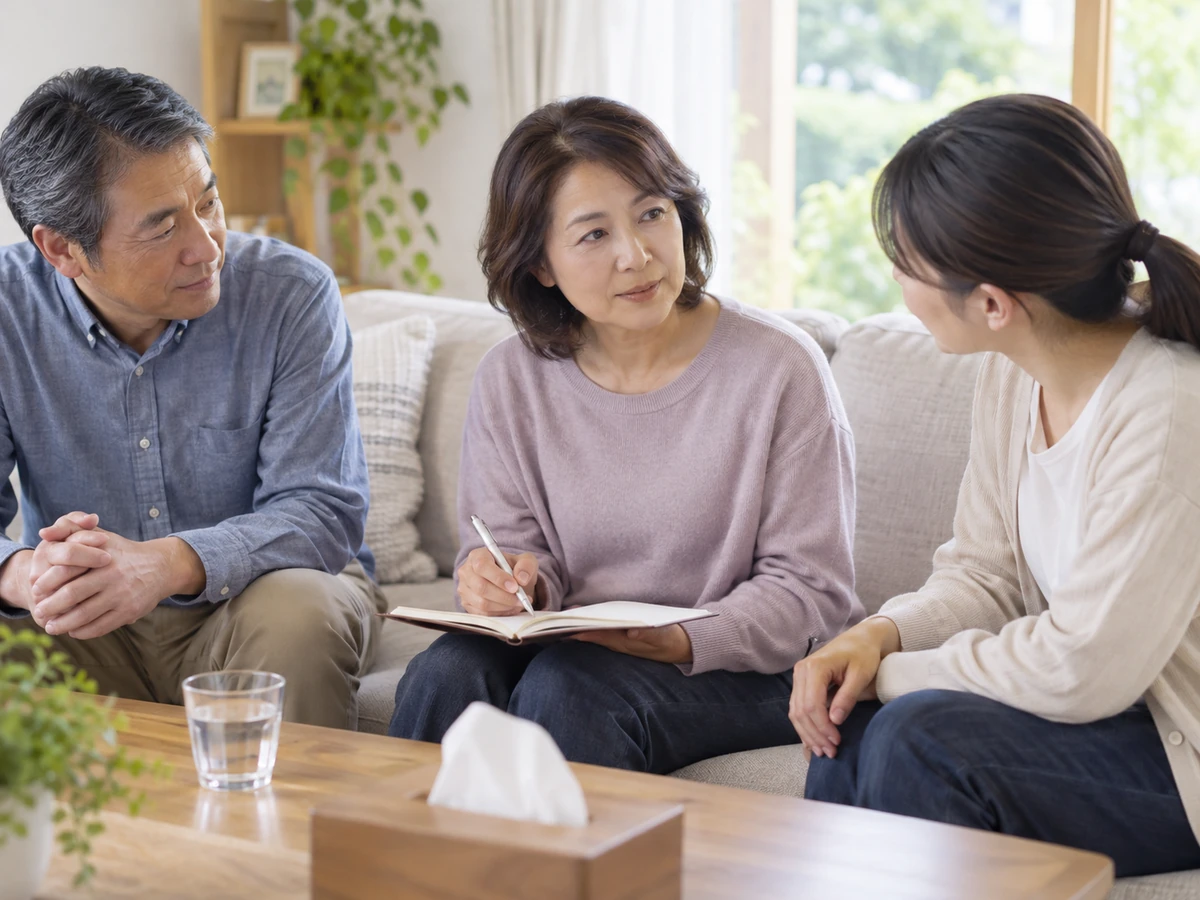 自宅で家族の話を聞きながら、女性がノートに書き留める様子