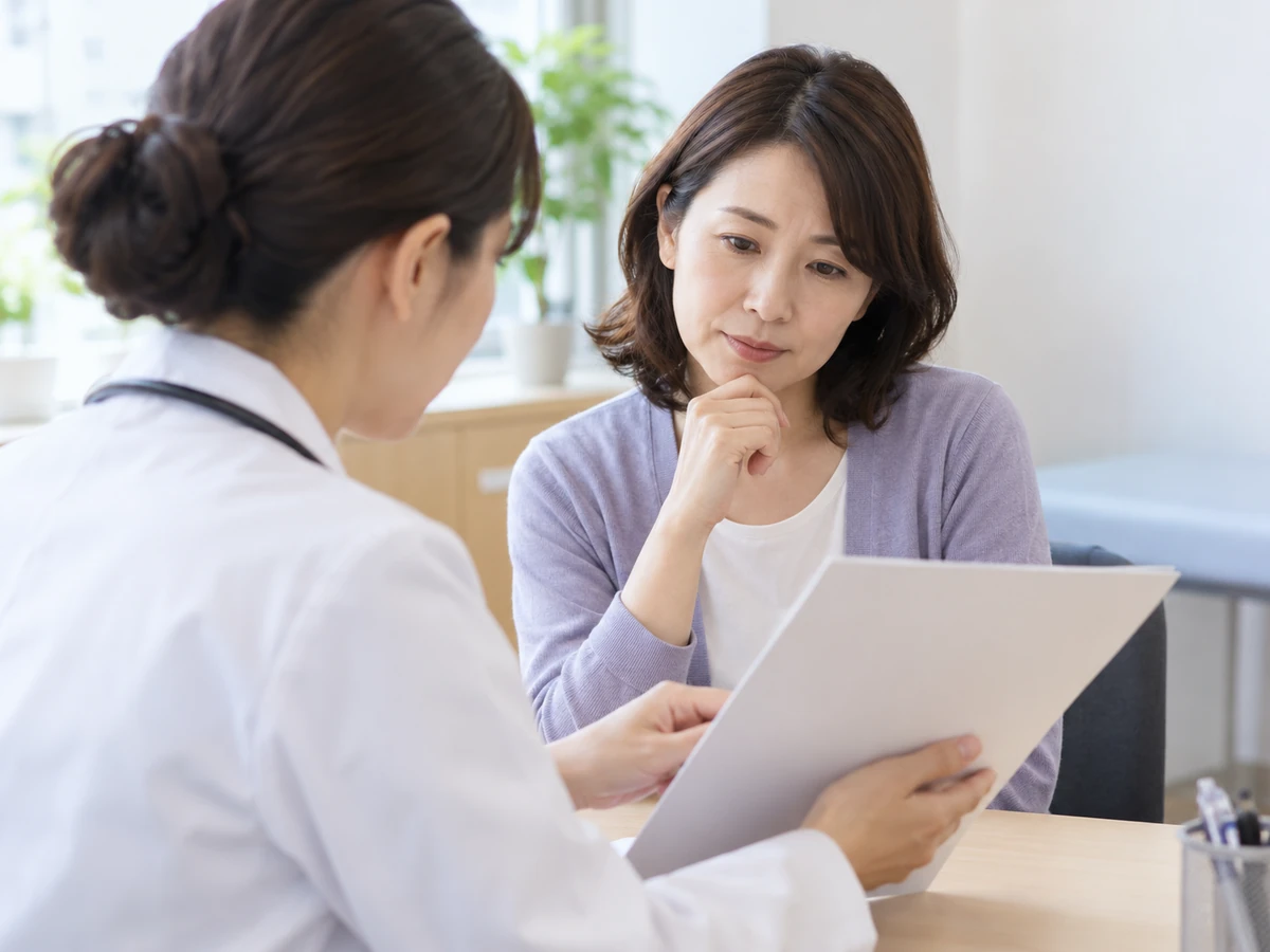 検査資料を見ながら女性医師の説明を聞く女性。