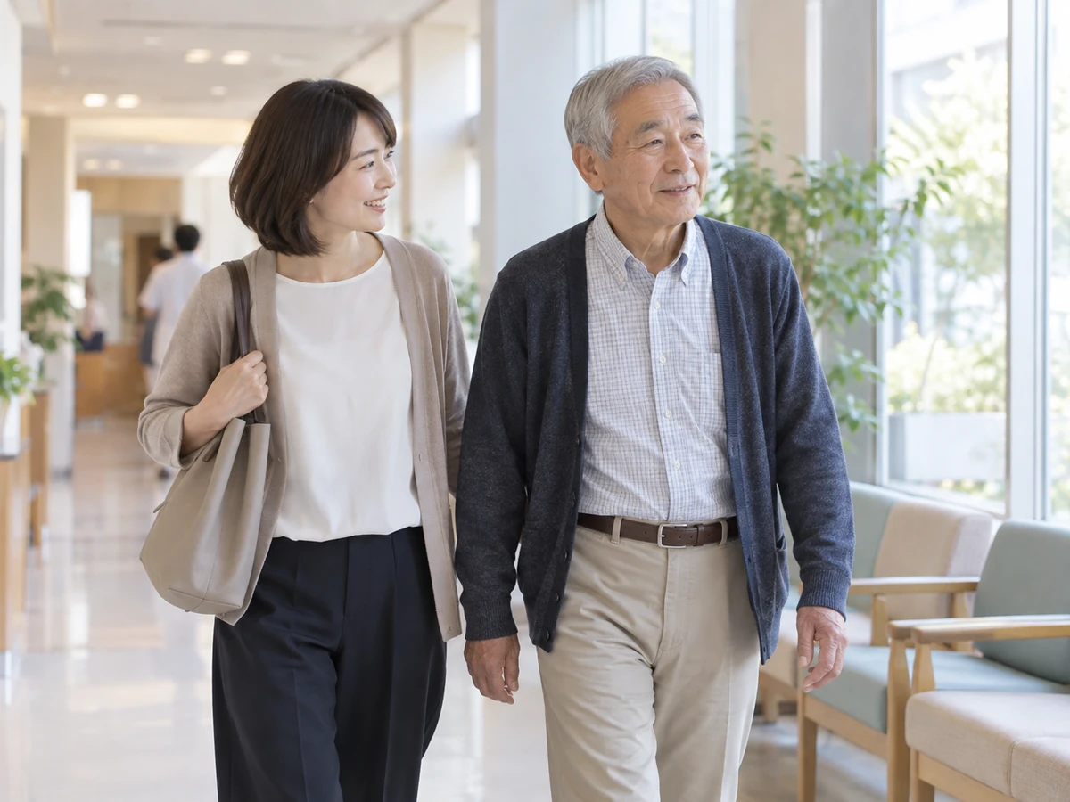 明るい外来の廊下を、男性と家族の女性が並んで歩いている。