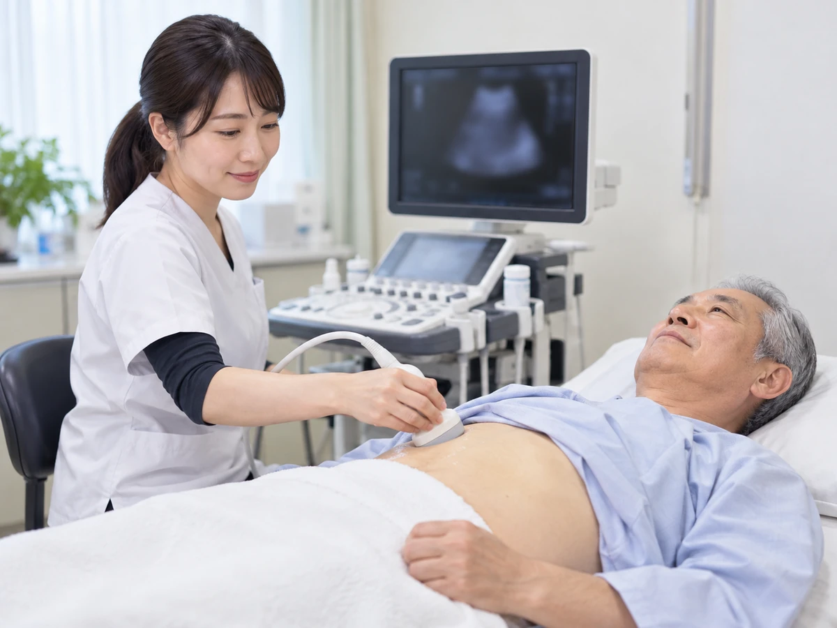 腹部に超音波プローブを当てて検査を受ける男性