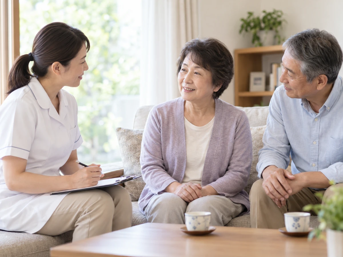 自宅のソファで夫婦が看護師と話している。