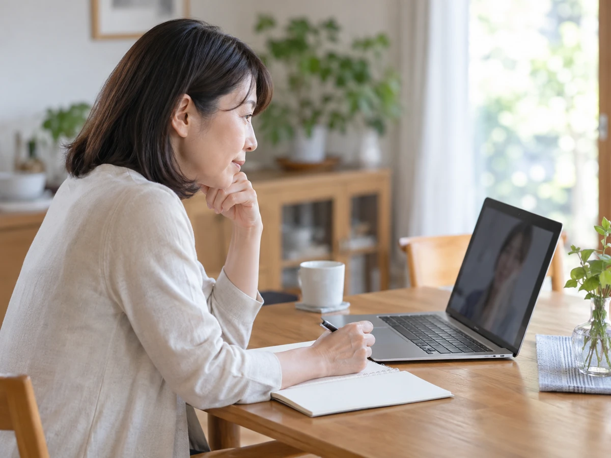 自宅で女性がノートを取りながらパソコンでオンライン相談をしている様子