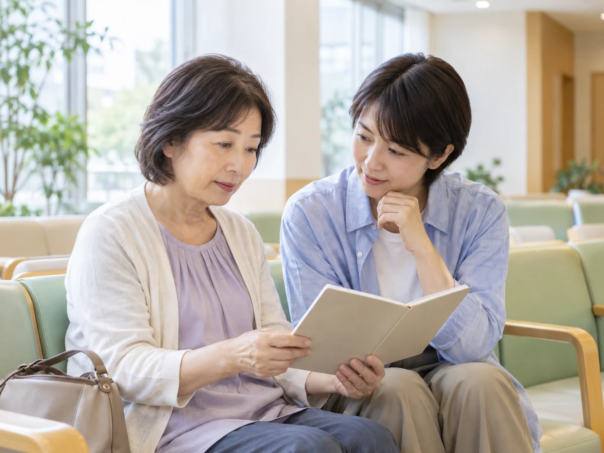 待合室で二人の女性がノートを開き、確認したいことを話している。