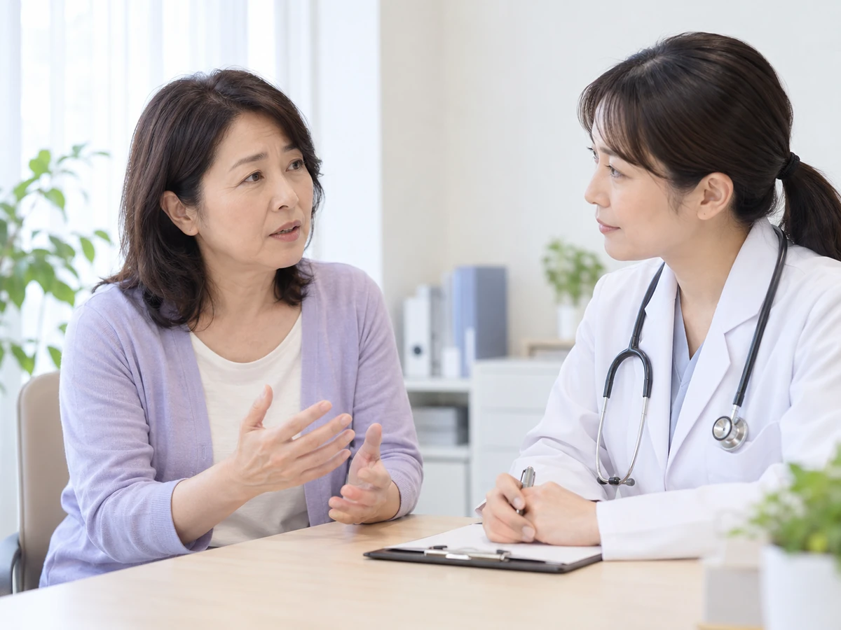 診察室で女性が医師に質問をし、医師が話を聴いている。