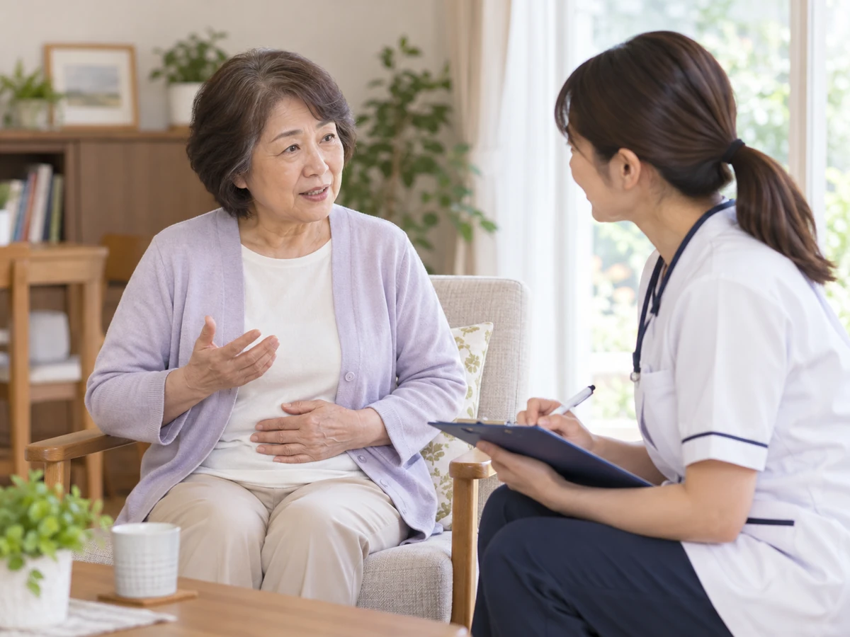 自宅で腹部の状態を訪問看護師に伝える女性