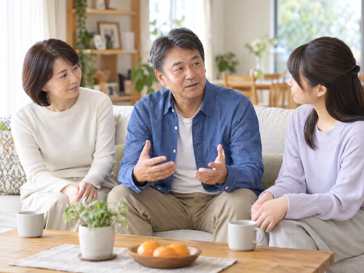 自宅のソファで家族と気持ちを話し合う男性のイメージ